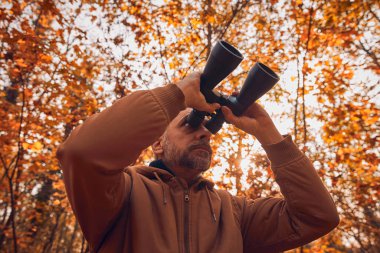 Kuşları ve diğer hayvanları dürbünle gözlemleyen amatör kuş gözlemcisi..