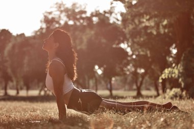 Sıcak bir yaz gününde parkta yoga ve esneme egzersizleri yapan bir kadın..