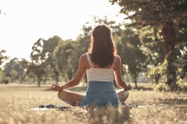Sıcak bir yaz gününde parkta yoga ve esneme egzersizleri yapan bir kadın..