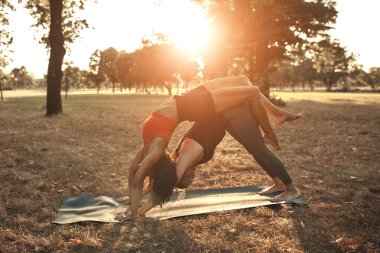 Sıcak ve güneşli bir yaz gününde iki kadın parkta yoga yapıyor ve esneme hareketleri yapıyor..