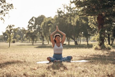 Sıcak bir yaz gününde parkta yoga ve esneme egzersizleri yapan bir kadın..