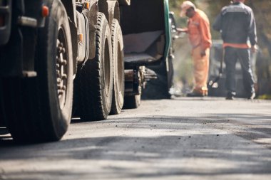 İnşaat işçileri kamu caddesinde yeni bir asfalt tabakası üzerinde çalışıyorlar..