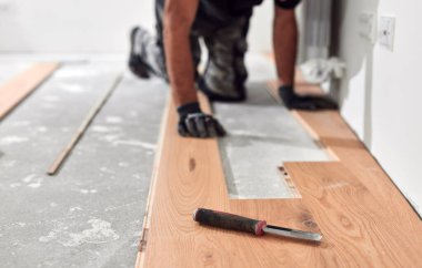 Profesyonel tamirci yeni bir daireye kaplama döşeme kuruyor..