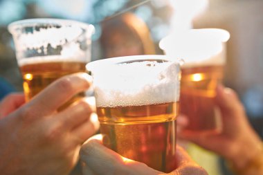 İnsanlar ellerinde bira bardakları tutarak yaz tatilinin tadını çıkarıyorlar..