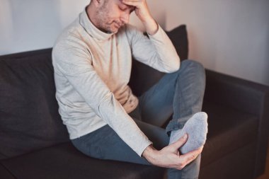 Ayak bileği ve ayak ağrısı olan bir adam..