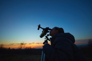 Amatör astronom teleskop kullanarak yıldızları, Ay 'ı, gezegenleri ve diğer gök cisimlerini doğadaki bir alandan izliyor..