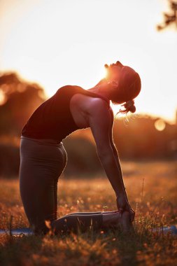 Sıcak bir yaz gününde parkta yoga ve esneme egzersizleri yapan bir kadın..