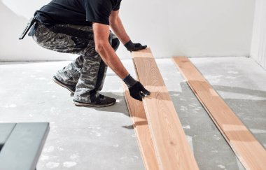 Profesyonel tamirci yeni bir daireye kaplama döşeme kuruyor..