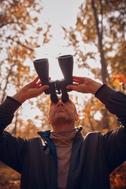 Kuşları ve diğer hayvanları dürbünle gözlemleyen amatör kuş gözlemcisi..
