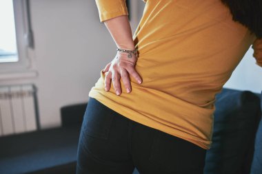 Kalçası, sırtı ve siyatik ağrısı olan bir kadın..