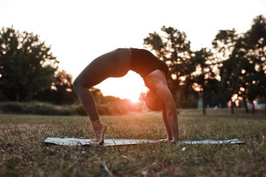 Sıcak bir yaz gününde parkta yoga ve esneme egzersizleri yapan bir kadın..