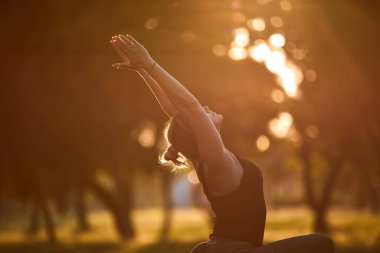 Sıcak bir yaz gününde parkta yoga ve esneme egzersizleri yapan bir kadın..