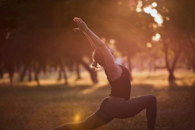 Sıcak bir yaz gününde parkta yoga ve esneme egzersizleri yapan bir kadın..