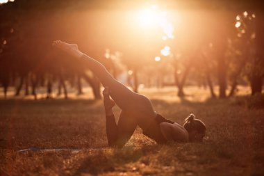Sıcak bir yaz gününde parkta yoga ve esneme egzersizleri yapan bir kadın..