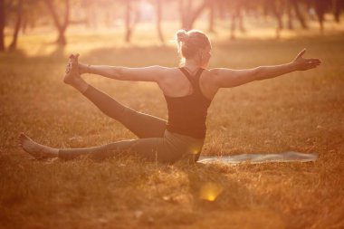Sıcak bir yaz gününde parkta yoga ve esneme egzersizleri yapan bir kadın..