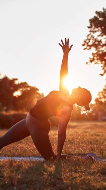 Sıcak bir yaz gününde parkta yoga ve esneme egzersizleri yapan bir kadın..