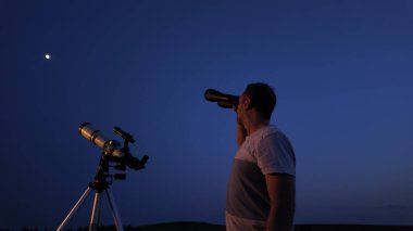 Amatör astronom teleskop ve dürbün kullanarak yıldızları, Ay 'ı, gezegenleri ve diğer gök cisimlerini doğadaki bir alandan izliyor..