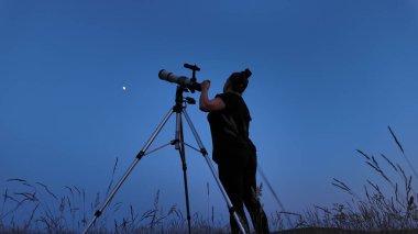 Amatör astronom teleskop kullanarak yıldızları, Ay 'ı, gezegenleri ve diğer gök cisimlerini doğadaki bir alandan izliyor..