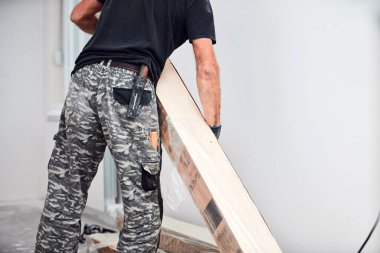 Profesyonel tamirci yeni bir daireye kaplama döşeme kuruyor..