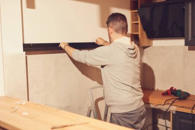 Tamirci mutfak dolaplarını ve rafları monte ediyor ve onarıyor..