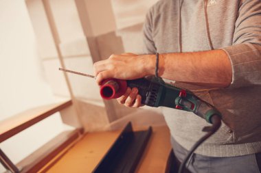 Tamirci mutfak dolapları ve raf montajı için matkap kullanıyor..