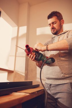 Tamirci mutfak dolapları ve raf montajı için matkap kullanıyor..