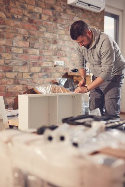 Yeni bir dairede çalışan ve mobilya montajlayan bir adam..