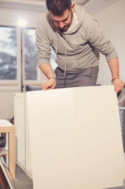 Yeni bir dairede çalışan ve mobilya montajlayan bir adam..