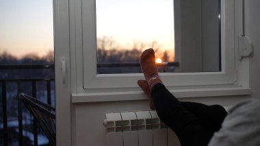 Soğuk bir kış gününde ev ısıtıcı radyatörde çoraplı bir kadının ayakları..