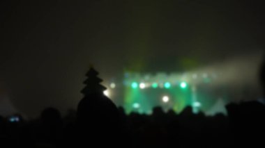 Sahne ışıkları olan, bulanık fotoğraflı konser kalabalığının siluetleri..