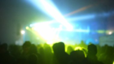 Sahne ışıkları olan, bulanık fotoğraflı konser kalabalığının siluetleri..