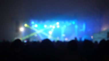 Sahne ışıkları olan, bulanık fotoğraflı konser kalabalığının siluetleri..