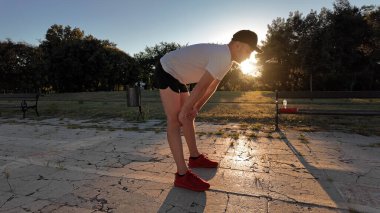 Adam gün batımında spor yaptıktan sonra şehir parkında koşuya çıkıyor..