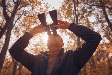 Kuşları ve diğer hayvanları dürbünle gözlemleyen amatör kuş gözlemcisi..