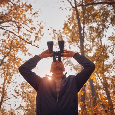 Kuşları ve diğer hayvanları dürbünle gözlemleyen amatör kuş gözlemcisi..