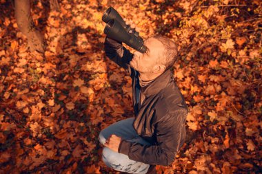 Kuşları ve diğer hayvanları dürbünle gözlemleyen amatör kuş gözlemcisi..
