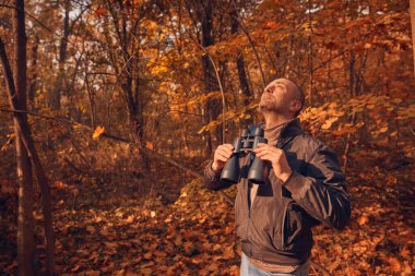 Kuşları ve diğer hayvanları dürbünle gözlemleyen amatör kuş gözlemcisi..