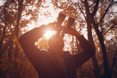 Kuşları ve diğer hayvanları dürbünle gözlemleyen amatör kuş gözlemcisi..