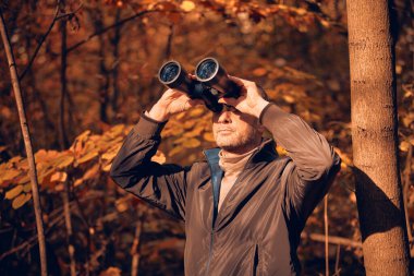 Kuşları ve diğer hayvanları dürbünle gözlemleyen amatör kuş gözlemcisi..