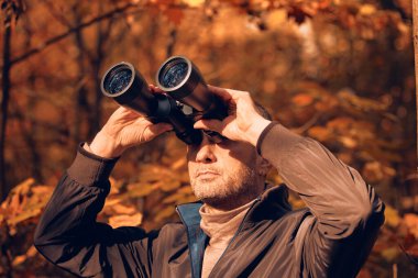 Kuşları ve diğer hayvanları dürbünle gözlemleyen amatör kuş gözlemcisi..