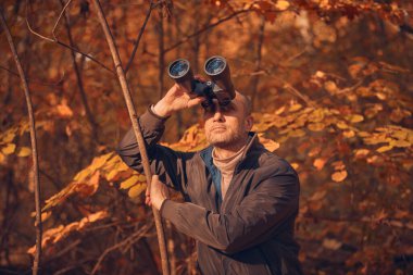 Kuşları ve diğer hayvanları dürbünle gözlemleyen amatör kuş gözlemcisi..