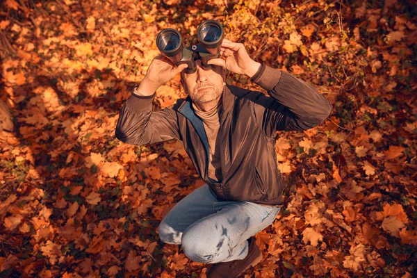 Kuşları ve diğer hayvanları dürbünle gözlemleyen amatör kuş gözlemcisi..