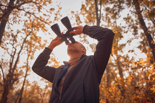 Kuşları ve diğer hayvanları dürbünle gözlemleyen amatör kuş gözlemcisi..