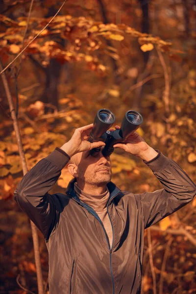 Kuşları ve diğer hayvanları dürbünle gözlemleyen amatör kuş gözlemcisi..