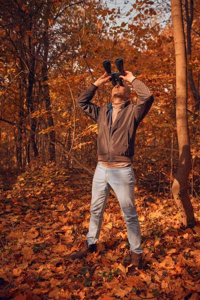 Kuşları ve diğer hayvanları dürbünle gözlemleyen amatör kuş gözlemcisi..