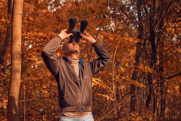 Kuşları ve diğer hayvanları dürbünle gözlemleyen amatör kuş gözlemcisi..