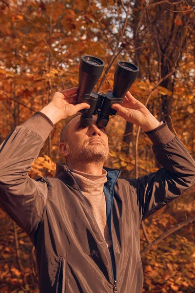 Kuşları ve diğer hayvanları dürbünle gözlemleyen amatör kuş gözlemcisi..