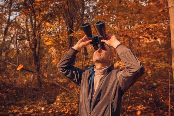 Kuşları ve diğer hayvanları dürbünle gözlemleyen amatör kuş gözlemcisi..