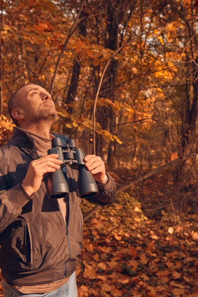 Kuşları ve diğer hayvanları dürbünle gözlemleyen amatör kuş gözlemcisi..