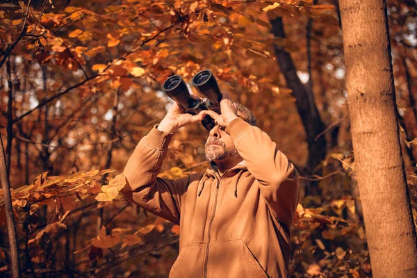 Kuşları ve diğer hayvanları dürbünle gözlemleyen amatör kuş gözlemcisi..